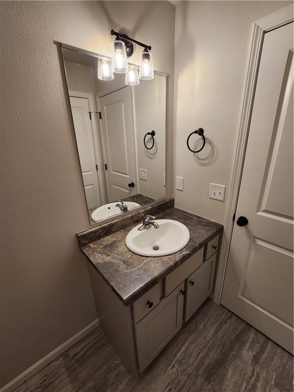 bathroom featuring baseboards, wood finished floors, and vanity