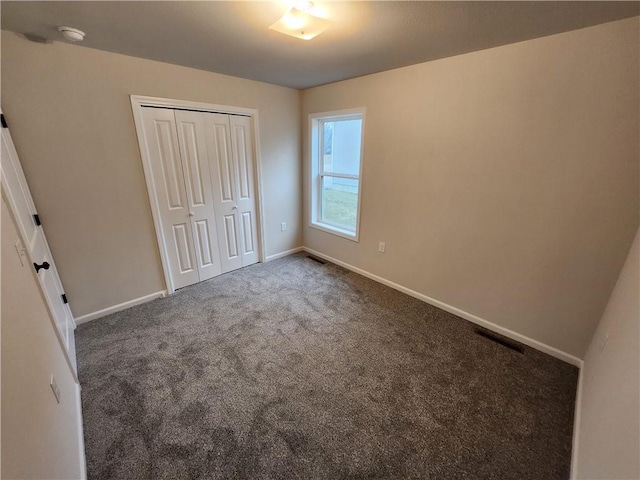 unfurnished bedroom with carpet, a closet, visible vents, and baseboards