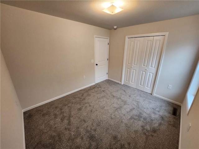 unfurnished bedroom with baseboards, carpet, visible vents, and a closet