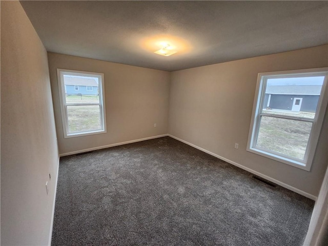 unfurnished room featuring dark carpet and baseboards