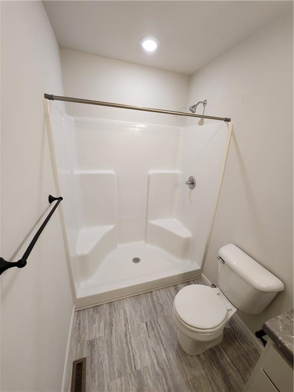 full bath with visible vents, toilet, wood finished floors, walk in shower, and vanity