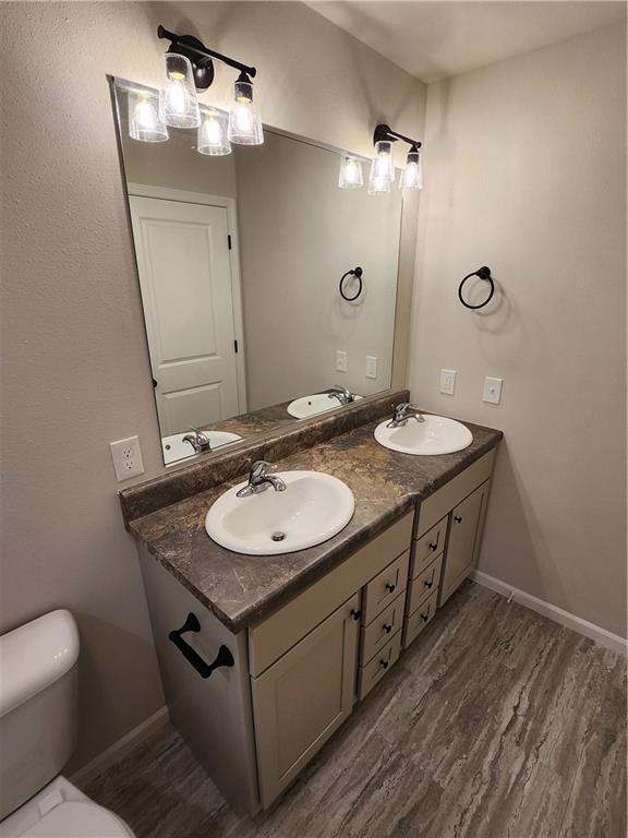 bathroom with toilet, a sink, and wood finished floors