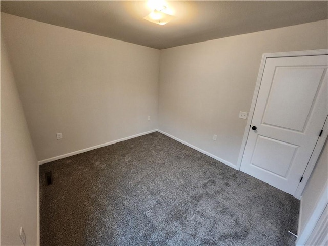 spare room with dark carpet and baseboards