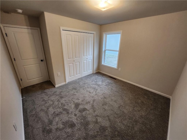 unfurnished bedroom with a closet, carpet flooring, visible vents, and baseboards