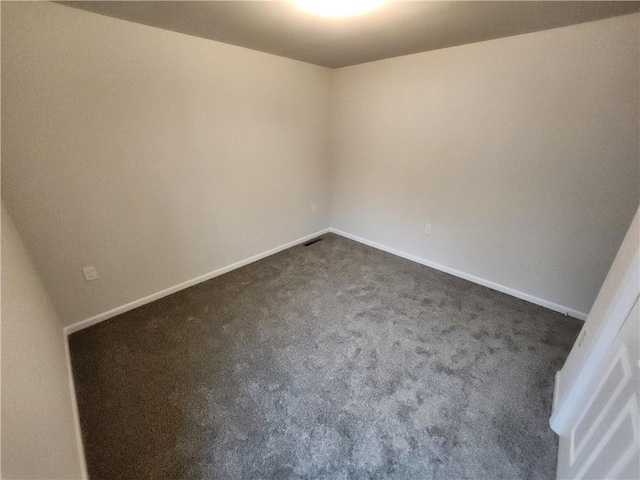 spare room featuring baseboards and dark carpet