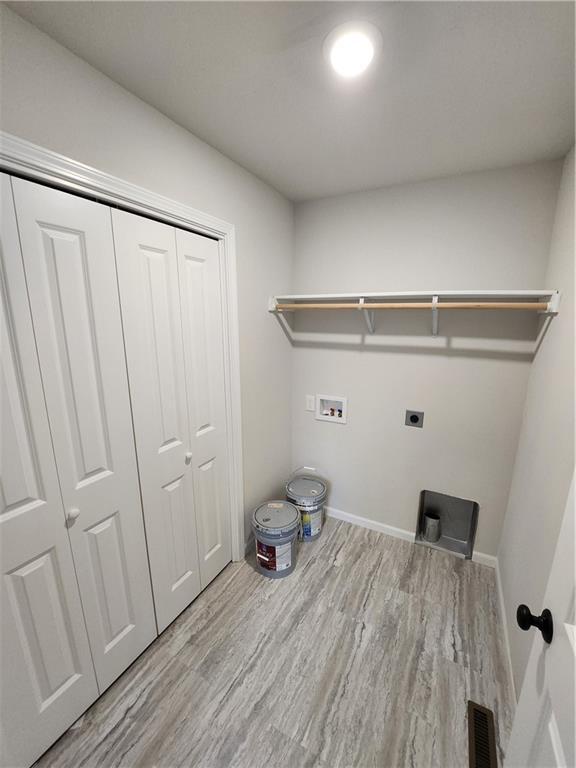 laundry room featuring laundry area, baseboards, wood finished floors, hookup for an electric dryer, and washer hookup