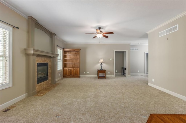 unfurnished living room featuring visible vents, crown molding, ceiling fan, light colored carpet, and a fireplace