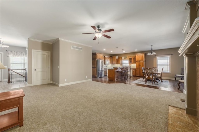 living room featuring ceiling fan with notable chandelier, light colored carpet, visible vents, and baseboards