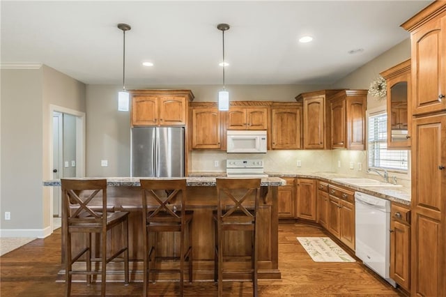 kitchen featuring a sink, a kitchen island, tasteful backsplash, dark wood finished floors, and white appliances