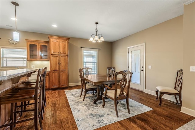 dining room featuring dark wood-type flooring, a notable chandelier, recessed lighting, and baseboards