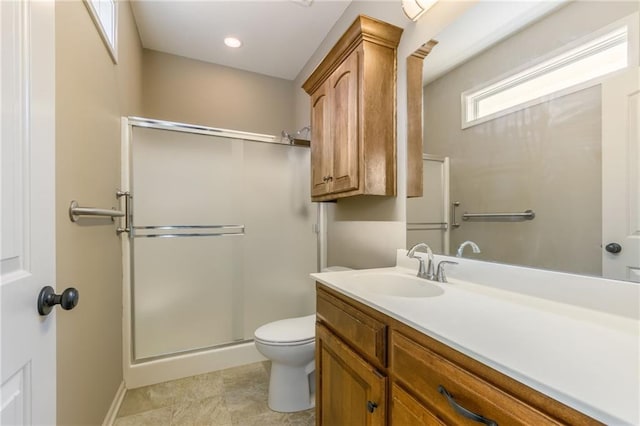 bathroom with a stall shower, toilet, vanity, and baseboards