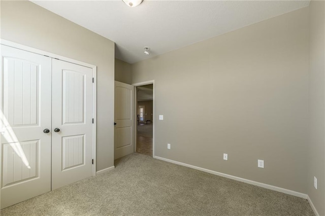 unfurnished bedroom with baseboards, a closet, and light carpet