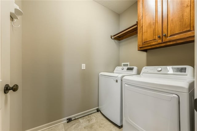 clothes washing area with washer and dryer, cabinet space, and baseboards