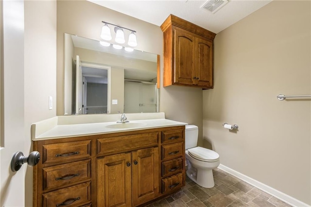 bathroom featuring vanity, baseboards, visible vents, stone finish flooring, and toilet