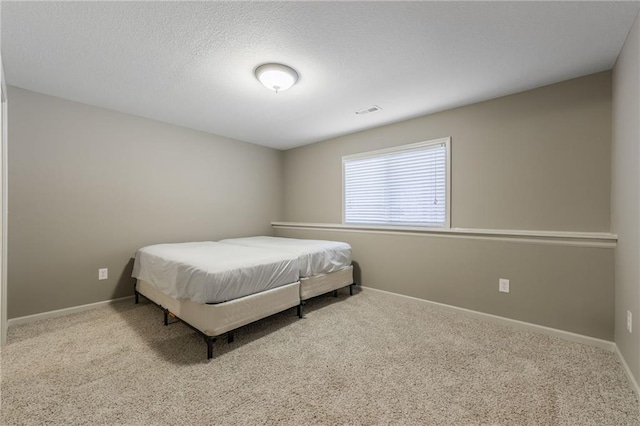 carpeted bedroom featuring visible vents, baseboards, and a textured ceiling