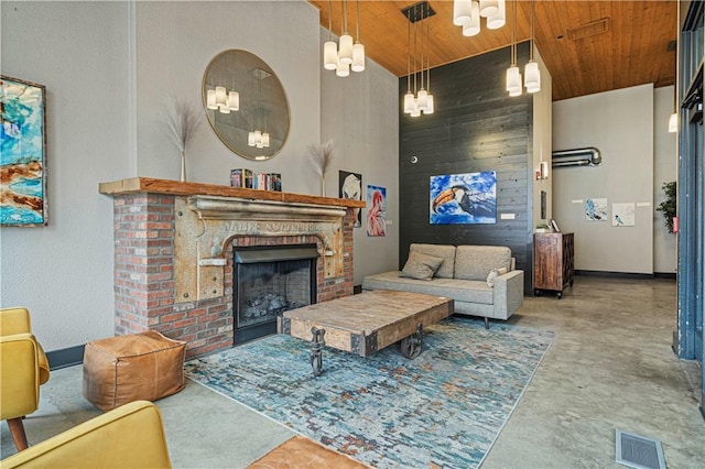 living area featuring finished concrete flooring, wooden ceiling, a fireplace, and visible vents