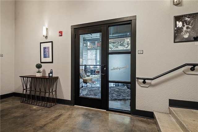 interior space featuring concrete flooring, a textured wall, and baseboards