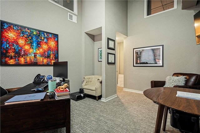 office featuring a towering ceiling, carpet, visible vents, and baseboards