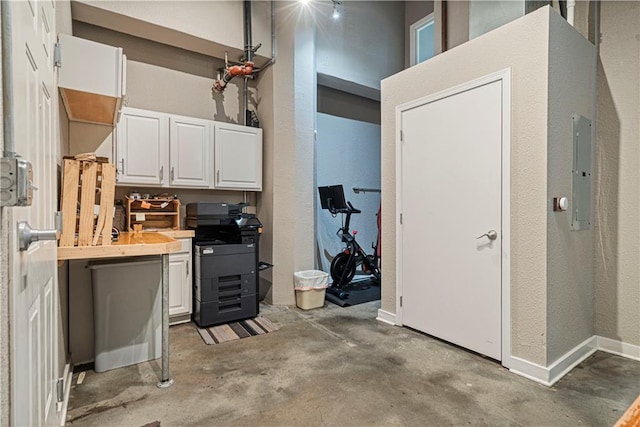 kitchen with electric panel, baseboards, light countertops, concrete floors, and white cabinetry