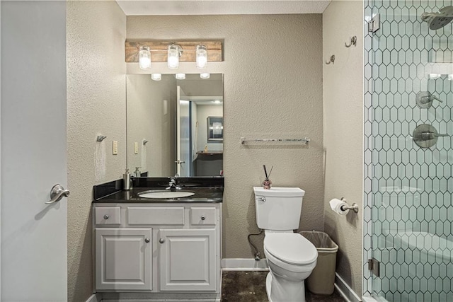 full bath with baseboards, tiled shower, vanity, and toilet