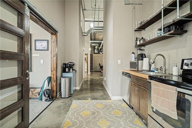 bar featuring appliances with stainless steel finishes, concrete flooring, a sink, and baseboards