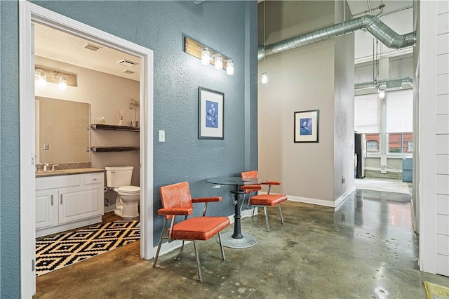 interior space featuring a textured wall, concrete floors, and baseboards