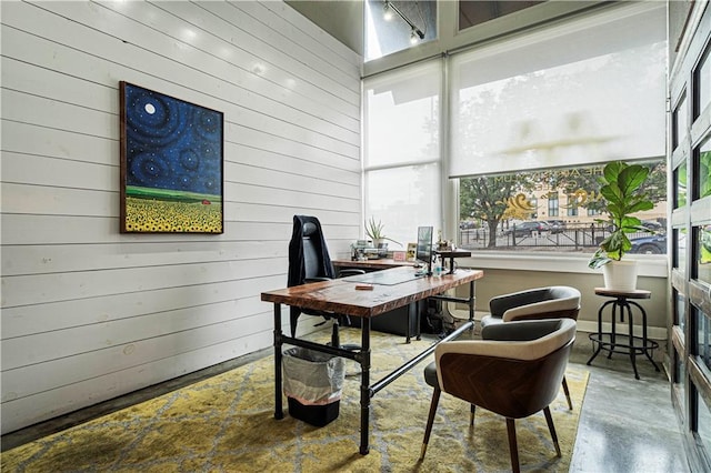 office area featuring wooden walls and concrete floors