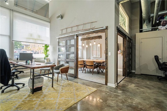 office area with concrete floors, a high ceiling, and baseboards