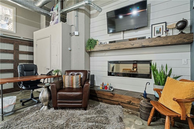 interior space with a glass covered fireplace and wooden walls