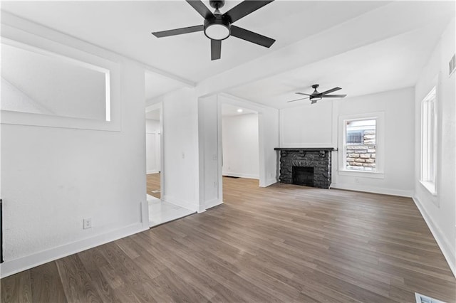 unfurnished living room with ceiling fan, a fireplace, wood finished floors, and baseboards