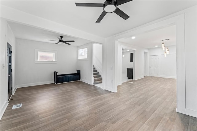 unfurnished living room featuring visible vents, stairway, baseboards, and wood finished floors