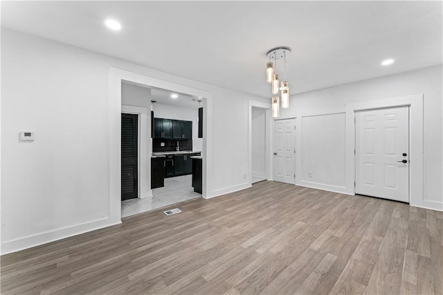 unfurnished dining area with light wood-type flooring, baseboards, visible vents, and recessed lighting