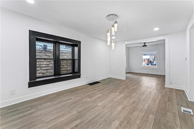 unfurnished dining area featuring ceiling fan, wood finished floors, visible vents, and baseboards