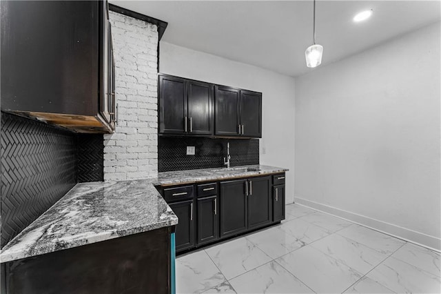 kitchen with light stone counters, a sink, baseboards, marble finish floor, and backsplash