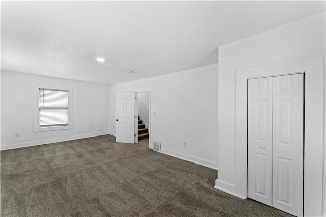 interior space with baseboards, visible vents, and dark carpet