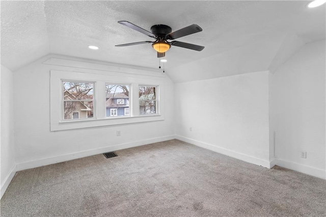 additional living space featuring carpet, vaulted ceiling, a textured ceiling, and baseboards