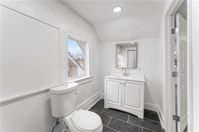 bathroom featuring toilet, vanity, baseboards, vaulted ceiling, and tile patterned floors