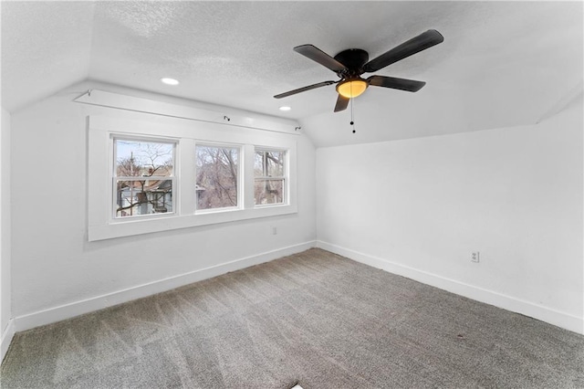 additional living space featuring lofted ceiling, a ceiling fan, carpet flooring, a textured ceiling, and baseboards