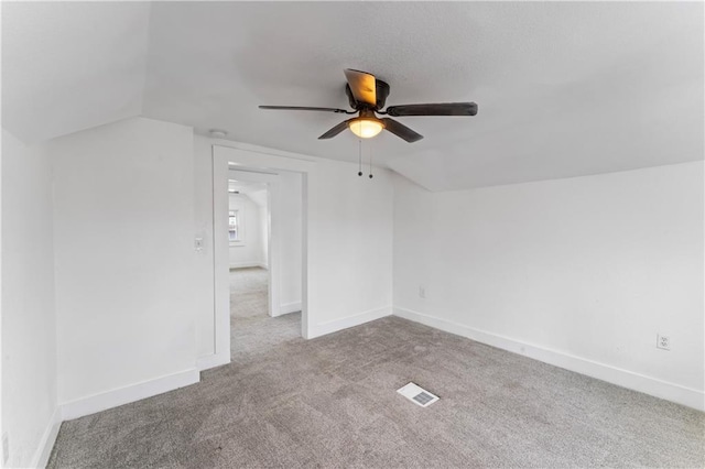 additional living space featuring visible vents, carpet flooring, vaulted ceiling, ceiling fan, and baseboards