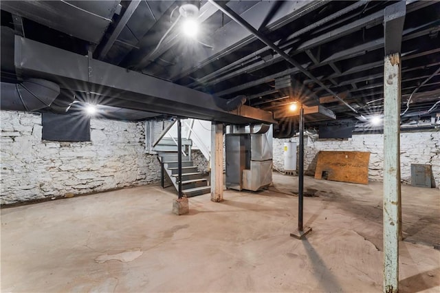 unfinished basement with heating unit, water heater, and stairs