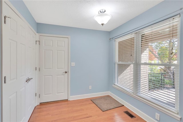 entryway with light wood finished floors, baseboards, visible vents, and a textured ceiling