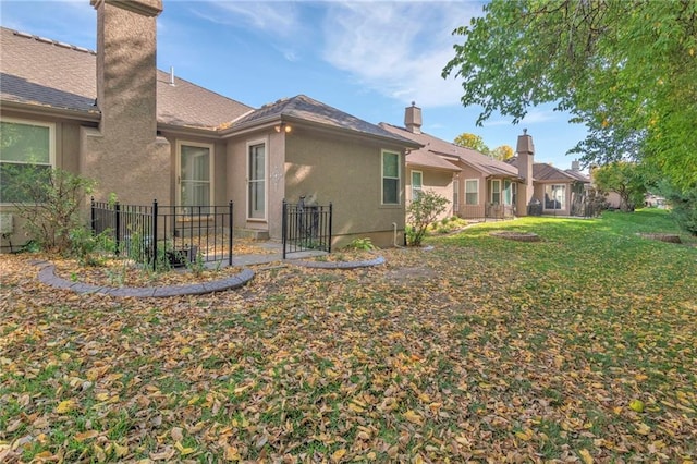 view of home's exterior with a yard, a chimney, fence, and stucco siding