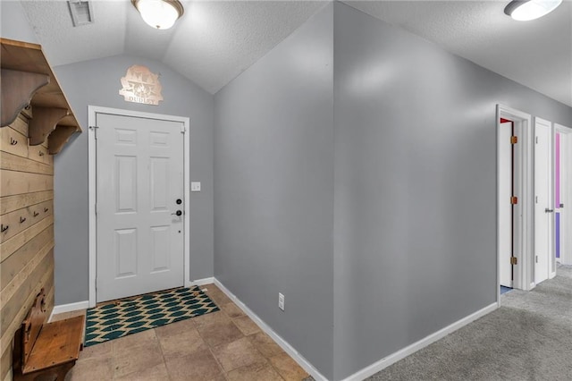 entrance foyer featuring visible vents, baseboards, a textured ceiling, and vaulted ceiling