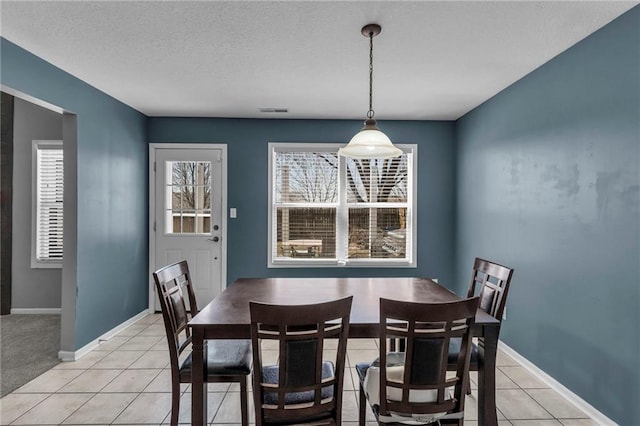 dining area with light tile patterned flooring, visible vents, a textured ceiling, and baseboards