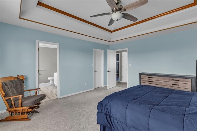 bedroom with a raised ceiling, carpet, baseboards, and ensuite bathroom