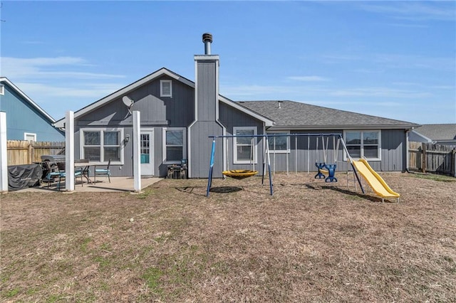 rear view of property with a playground, a lawn, a chimney, a fenced backyard, and a patio