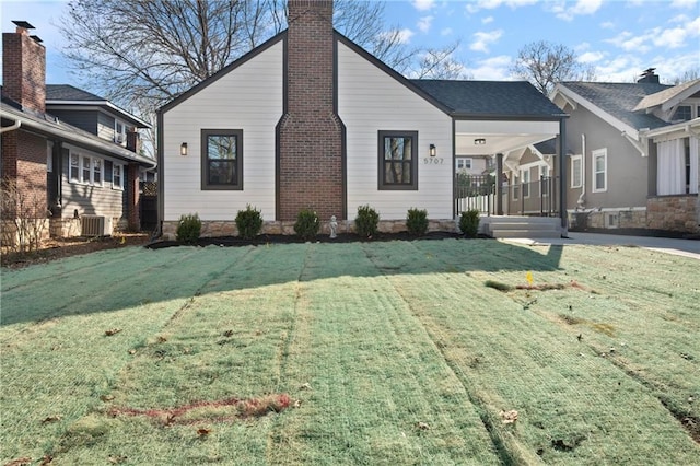 view of front of house with covered porch, a chimney, and a front yard