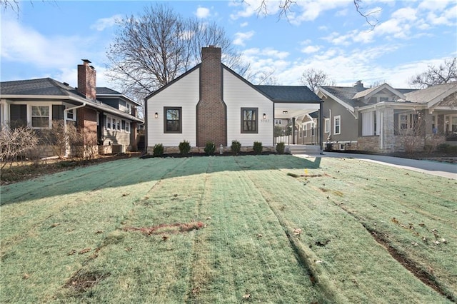 view of front facade featuring a porch, a chimney, and a front yard