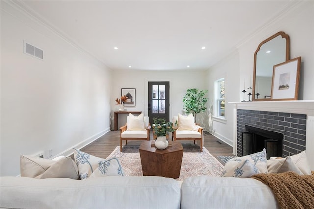 living room with visible vents, baseboards, a fireplace with flush hearth, and wood finished floors