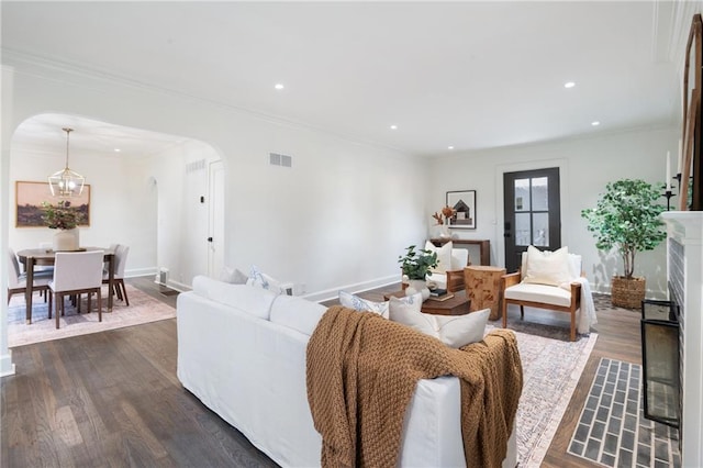 living area featuring arched walkways, visible vents, crown molding, and dark wood-style floors